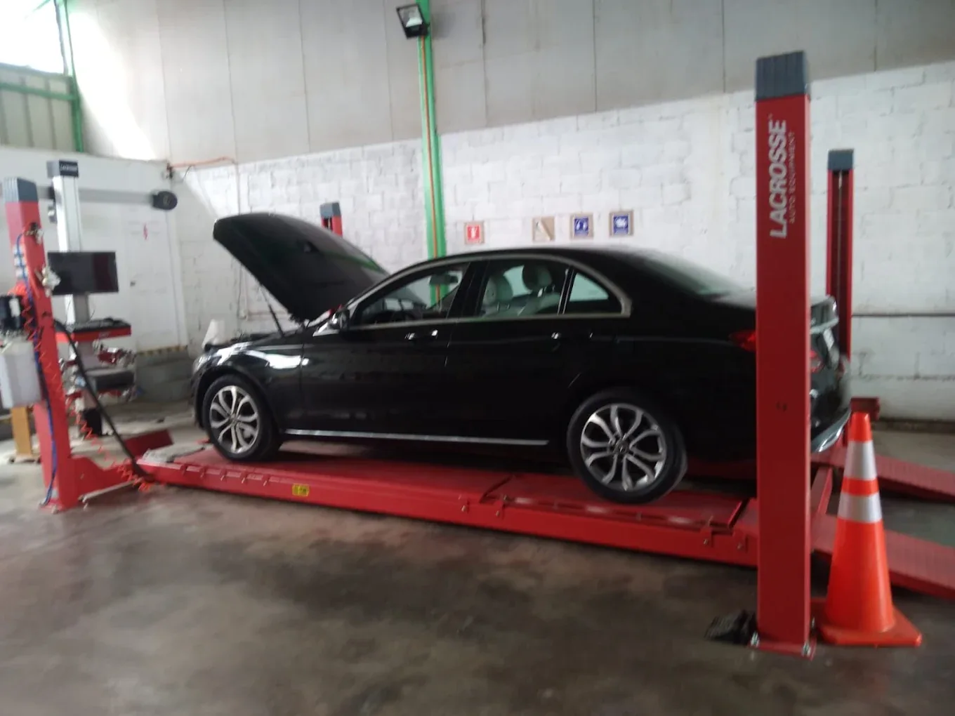 Sedán negro en plataforma de alineación dentro del taller